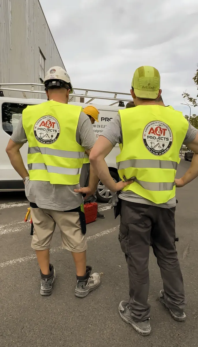 Twee medewerkers van A&T Projects in fluohesjes met logo